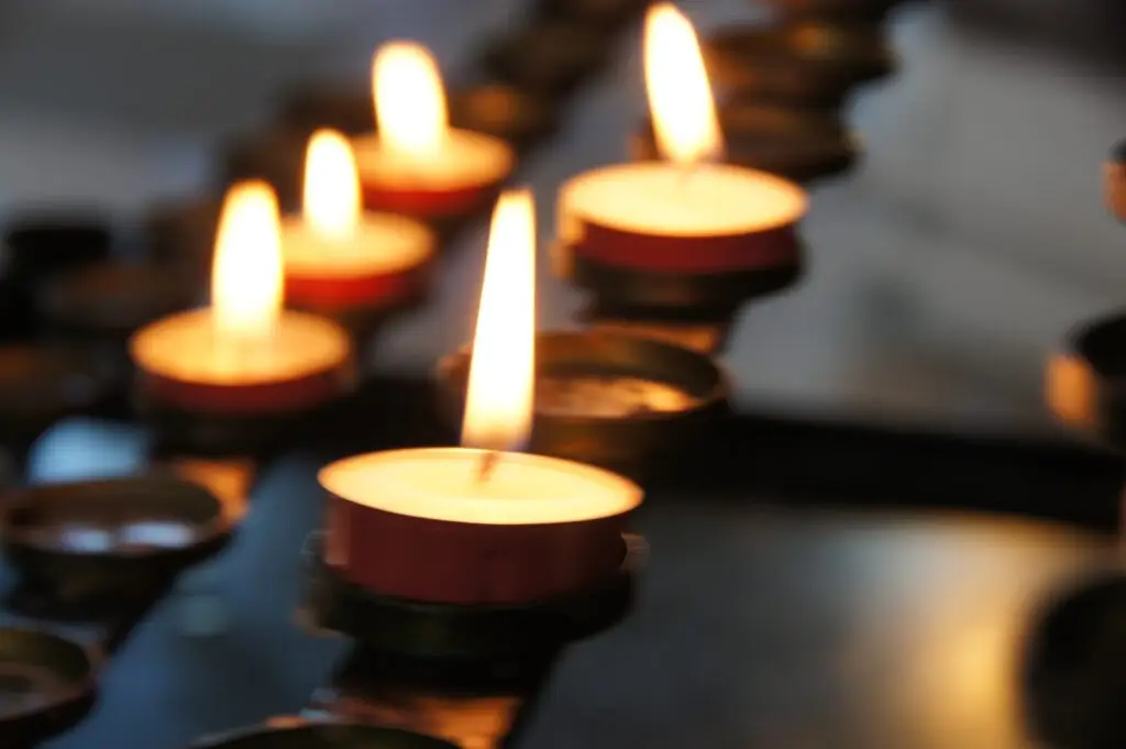 A row of lit tealight candles, slightly blured