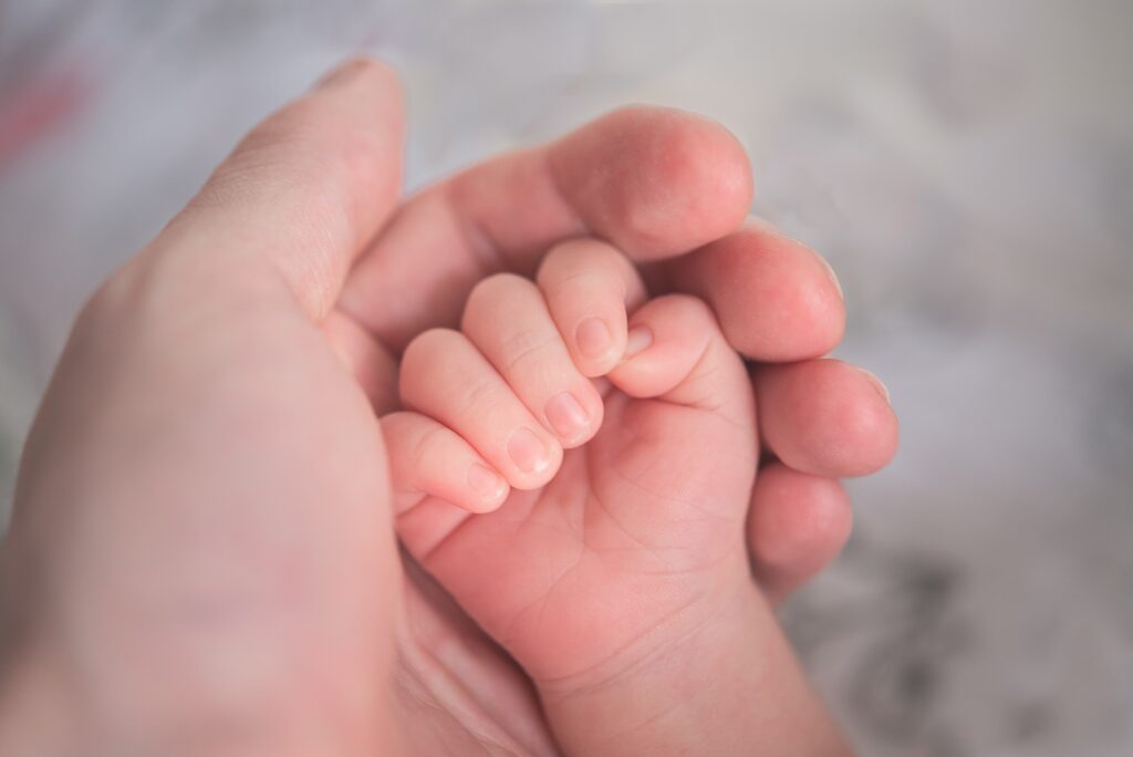A baby's hand cupped inside an adult's hand