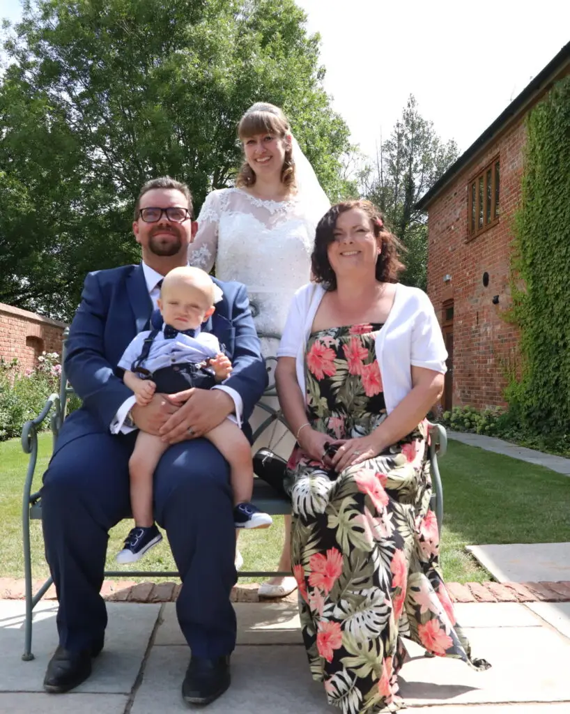 Image of married couple with young child next to celebrant on wedding day