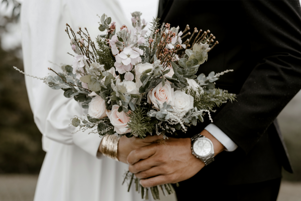 A newlywed couple holding a wedding bouquet